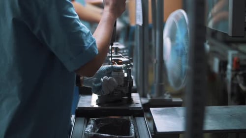 Un ingénieur visse un boulon sur des appareils métalliques sur une chaîne de montage. Travailleur rapproché