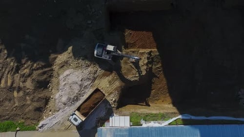Aerial View of Excavator Filling Dump Truck with Soil