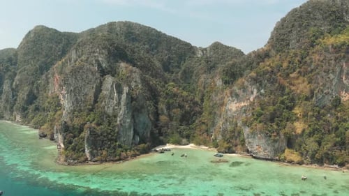 Tall Limestone cliffs adjacent to shallow emerald green shoreline in Tonsai Bay, Ko Phi Phi Don Isl