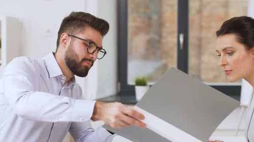 Professionals Discussing Documents in Bright Office Environment