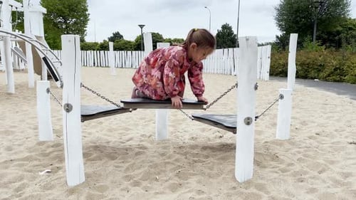 Child Girl Climbing Ropes and Obstacles on the Playground