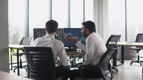 Two Men Traders Sitting at Desk at Office Together Monitoring Stocks Data Candle Charts Money Flow