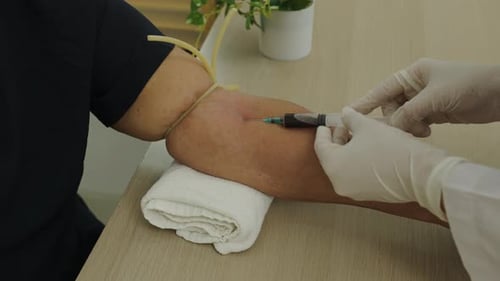 Close up of doctor or nurse taking a blood sample from arm vein with vacutainer. syringe to venipunc