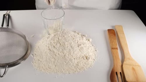 Chef Adds Flour to Flour Pile on Table