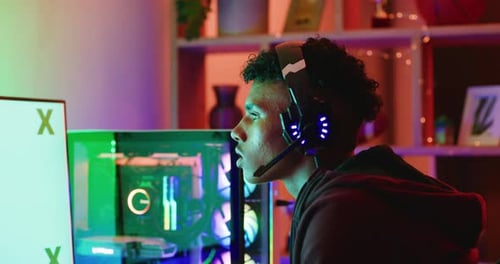 Jovem jogador jogando vídeo online em um monitor de computador com espaço de cópia em tela verde