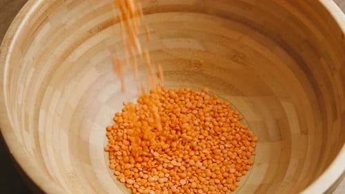 Bright Lentils Pouring into Wooden Bowl for Cooking