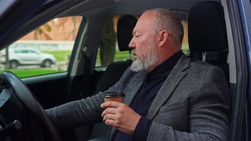 Homem idoso bebendo café no banco do motorista