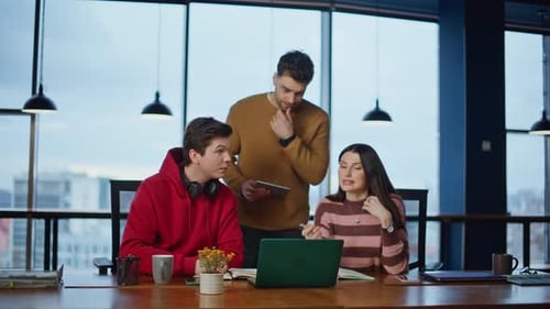 Colleagues Collaborate on Laptop in Modern Office