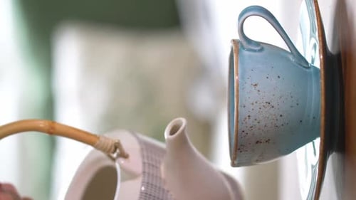 Vertikales Video, in dem frischen Kräutertee aus einer schönen Teekanne in eine blaue Tasse gegossen wird. Natürliches T brauen