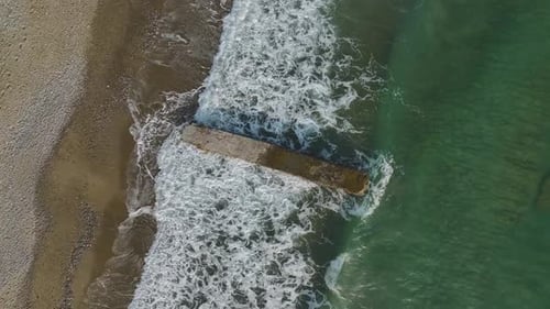 Serene Beach Scene Aerial of Stone Pier and Clear Blue Water