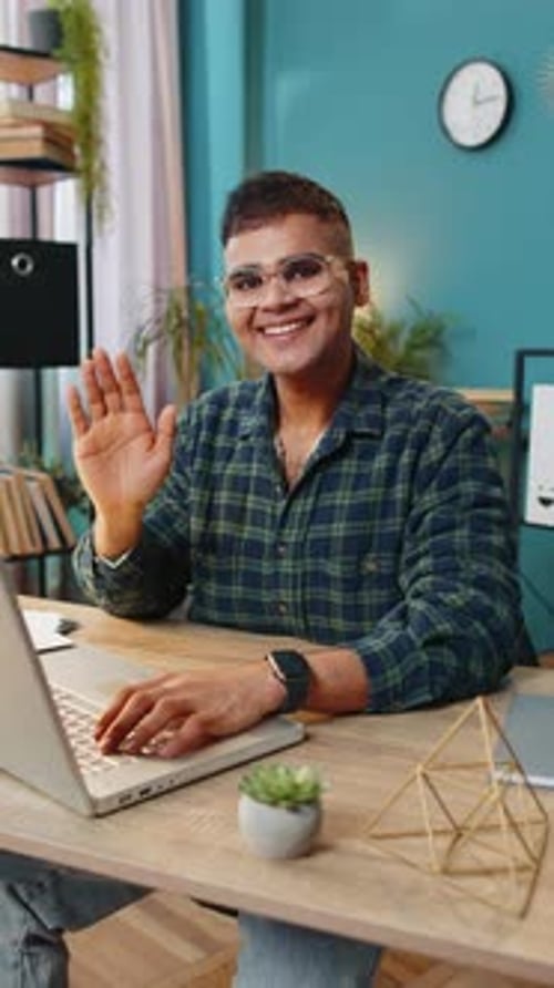 Smiling Young Adult Working on Laptop at Desk