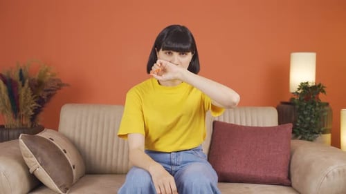 Young Woman Coughing into her Arm at Home