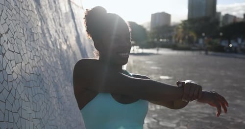 Woman Stretches Arms Near Urban Tile Mosaic Wall