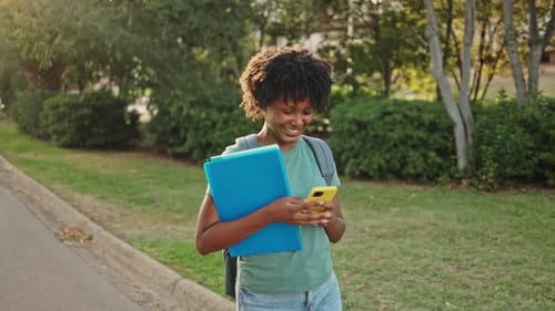 Student Smiling and Using Phone on College Campus