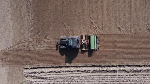 Aerial View of Tractor with Seeder Planting Seeds on Farmland