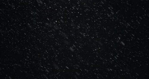 Winter snowfall at night snowing on city street in street light. Snow flakes falling in slow motion