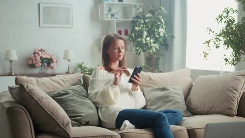Woman Relaxing on Couch Using Smartphone