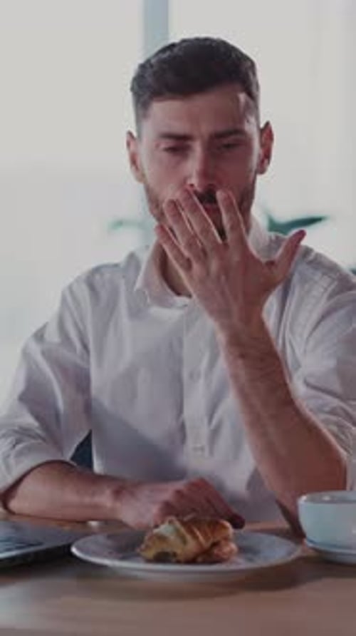 Man Counting Fingers During Laptop Work with Pastry