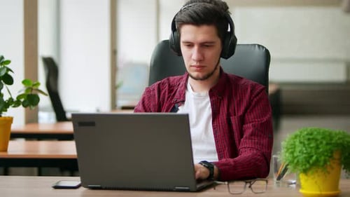 Young Adult Working on Laptop With Headphones