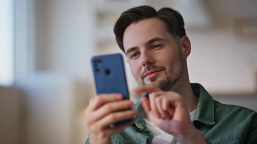 Man Using Smartphone and Smiling Indoors