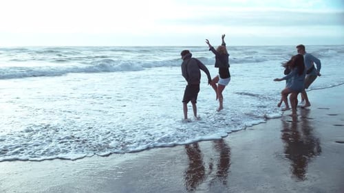 Friends Playfully Jumping in the Waves on Beach