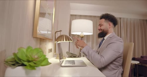 A Professional Man Engaged in Work at His Desk Located in a Contemporary Modern Hotel Room