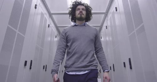 Young Adult Walks Through Narrow Server Room