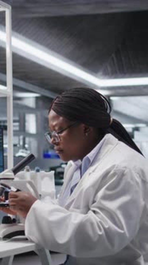 Vertical Video Black Female Expert Analyzing Samples in Chemistry Lab with Microscope
