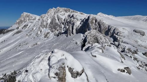 Snow-covered Strungile Mari Peak under a clear blue sky, Bucegi Mountains