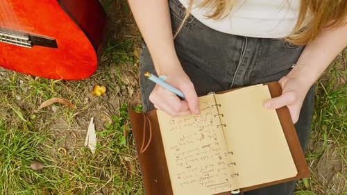 Female guitarist composer writes chords lyrics song book top down shot