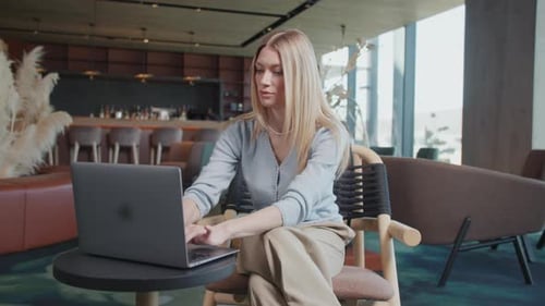 Close Up Attractive Blond Young Woman Using and Typing Laptop in a Cafe Sitting Smiling Feel Happy