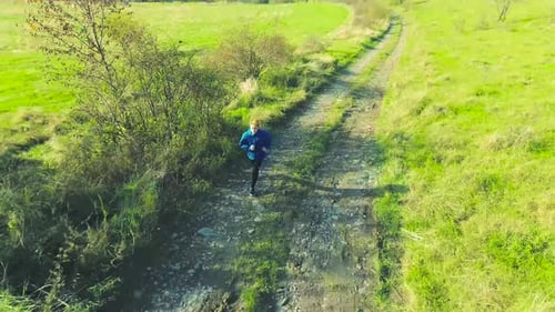 Young Fit Athlete Running in Green Sunny Autumn Nature