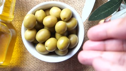 Bottle of Olive Oil and Fresh Olive in a Container on Table