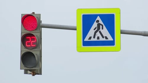 O semáforo verde pisca contra um céu claro e depois muda