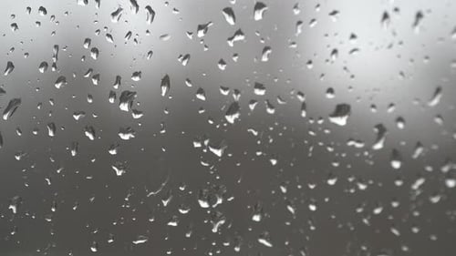 Raindrops Dripping Down a Window on a Cloudy Day