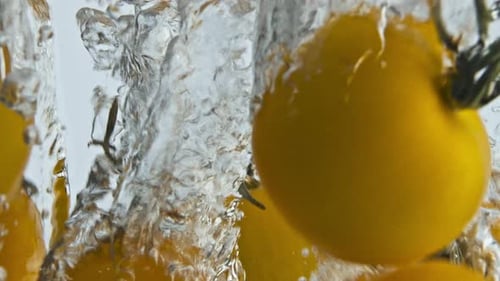 Yellow Tomatoes Plunging into Water Creating Bubbles