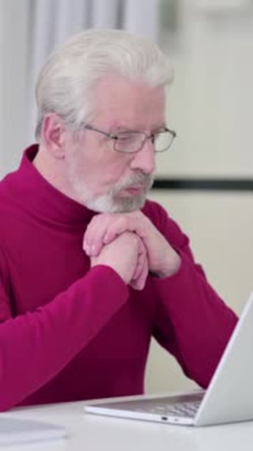 Senior Man Working on Laptop at Desk Indoors