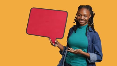 Smiling Woman Holding Red Speech Bubble Sign Studio Background
