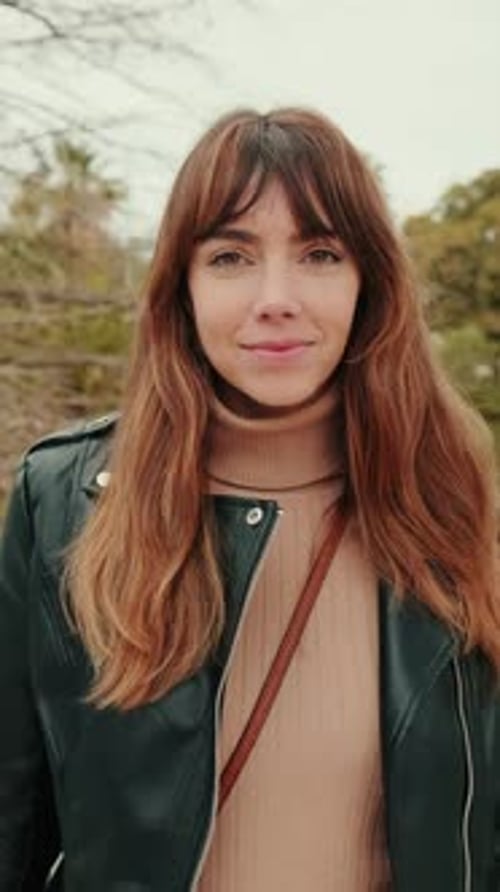 Vertical video, Happy attractive young woman looking at camera outside in park