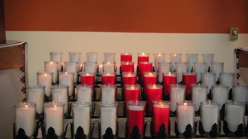 A Bunch of Red and White Candles are Lit Up in a Row Wide Shot