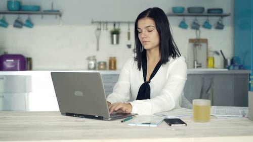 Woman Uses Laptop at Kitchen Table