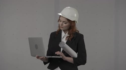 A Woman Architect Works on a Laptop Studies Plans Prints Reports Business Woman in a Protective