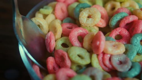 Close Up of Spoon Taking a Portion of Colorful Corn Rings From the Bowl