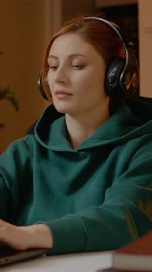 Focused woman with headphones working on laptop