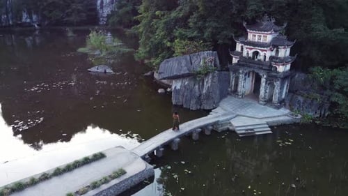 Aerial parallax view, Bich Dong Pagoda, female tourist, stone bridge