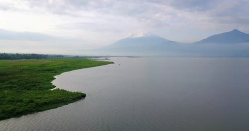 Luftbild eines riesigen Sees und der grünen Wiese am Seeufer mit Berg im Hintergrund - Rawa Pen