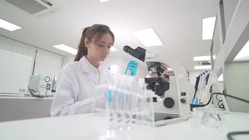 Woman Scientist Using Microscope in Modern Bright Lab