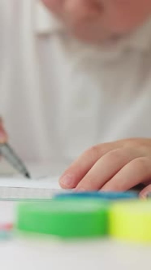 Child Drawing in Notebook with Pen Close Up