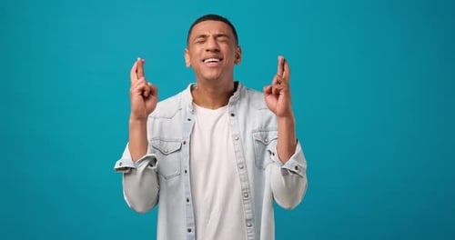 Young Man Crossing Fingers Hoping for Good Luck