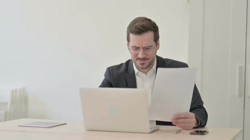 Upset Man Reading Paper at Office Desk